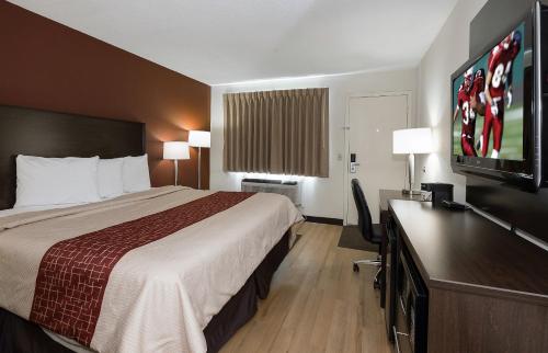 a hotel room with a bed and a flat screen tv at Red Roof Inn Dayton Huber Heights in Dayton
