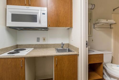 a small kitchen with a sink and a microwave at HomeTowne Studios by Red Roof Houston - Northwest in Houston