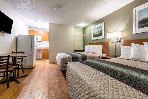 a hotel room with two beds and a table and a kitchen at HomeTowne Studios by Red Roof Houston - Northwest in Houston