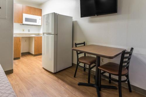 a small kitchen with a table and a refrigerator at HomeTowne Studios by Red Roof Houston - Northwest in Houston