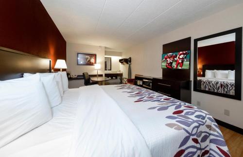 a hotel room with a large bed and a flat screen tv at Red Roof Inn Lansing East - MSU in Lansing
