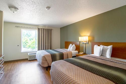 a hotel room with two beds and a window at HomeTowne Studios by Red Roof Chicago - Waukegan in Waukegan