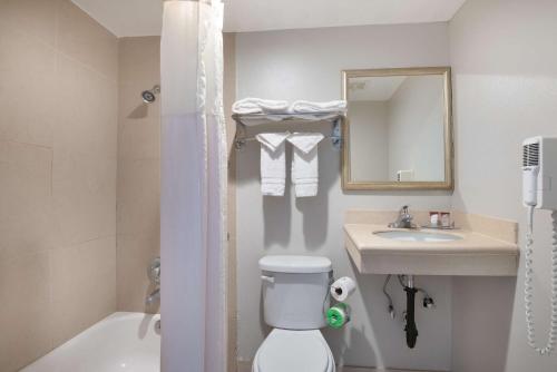 a bathroom with a toilet and a sink and a mirror at Red Roof Inn Tucson Downtown - University in Tucson