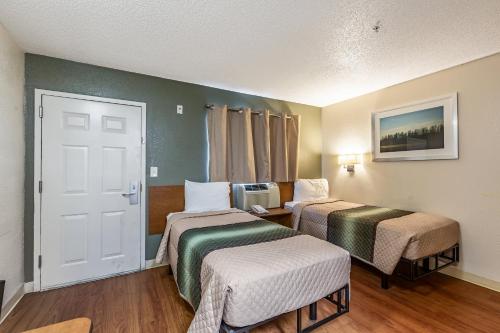 a hotel room with two beds and a door at HomeTowne Studios by Red Roof Atlanta - Chamblee in Atlanta