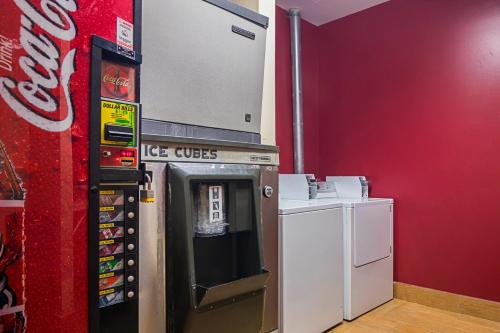 a coca cola machine next to a red wall at Red Roof Inn & Suites Lake Orion / Auburn Hills in Lake Orion