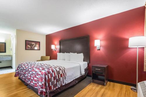 a hotel room with a bed and a red wall at Red Roof Inn Cincinnati Airport–Florence/ Erlanger in Erlanger