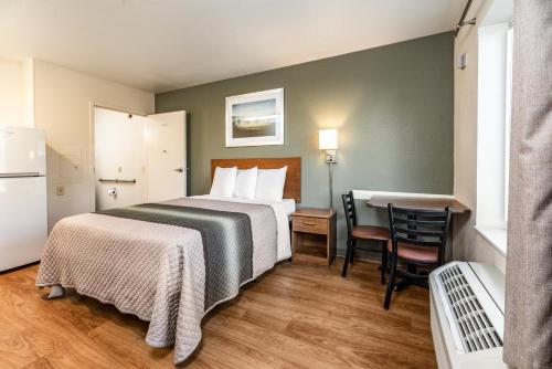 a hotel room with a bed and a table and chairs at HomeTowne Studios by Red Roof Fresno - West in Fresno
