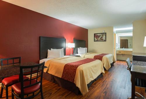 Habitación de hotel con 2 camas, mesa y sillas en Red Roof Inn & Suites Scottsboro, en Scottsboro