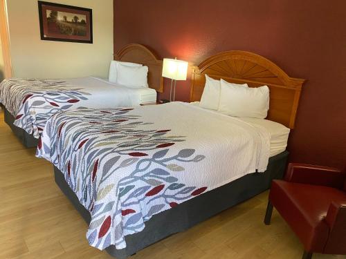 a hotel room with two beds and a chair at Red Roof Inn Wheelersburg in Wheelersburg
