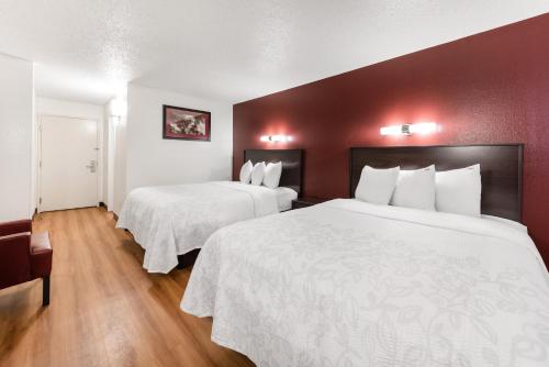 a hotel room with two beds with white sheets at Red Roof Inn PLUS+ Columbus - Worthington in Columbus