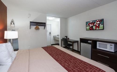 a hotel room with a bed and a desk with a microwave at Red Roof Inn Lancaster Strasburg in Lancaster