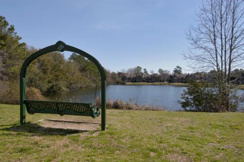 a park bench in the grass next to a lake at Red Roof Inn PLUS+ Mt Pleasant - Patriots Point in Charleston