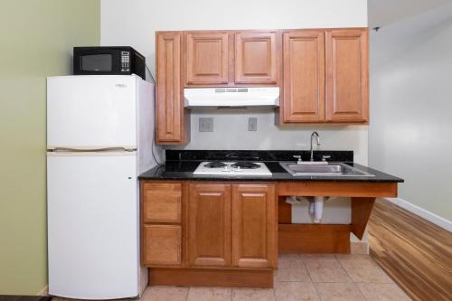 a kitchen with wooden cabinets and a white refrigerator at Red Roof Inn & Suites Wilson in Wilson