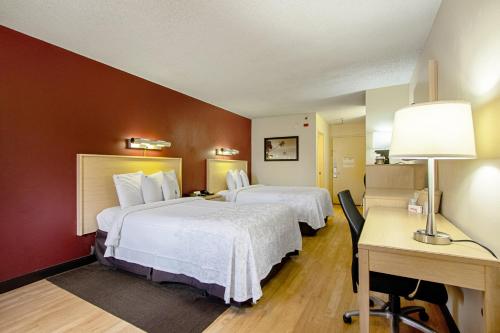 a hotel room with two beds and a desk at Red Roof Inn PLUS+ West Palm Beach in West Palm Beach