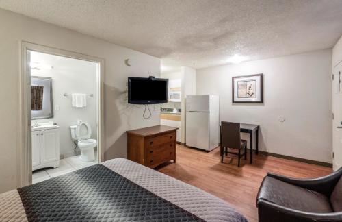 a bedroom with a bed and a desk with a television at HomeTowne Studios by Red Roof Orlando South in Orlando
