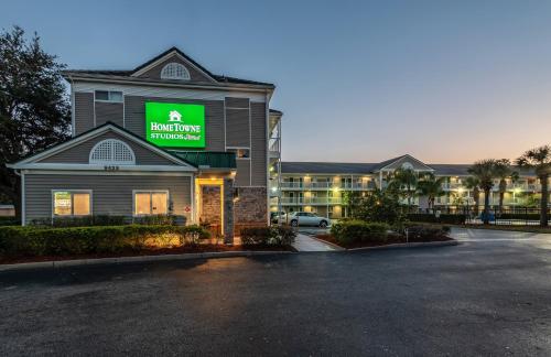 a hotel with a parking lot in front of a building at HomeTowne Studios by Red Roof Orlando South in Orlando