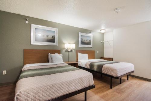a hotel room with two beds and two pictures on the wall at HomeTowne Studios by Red Roof Raleigh – Durham in Durham
