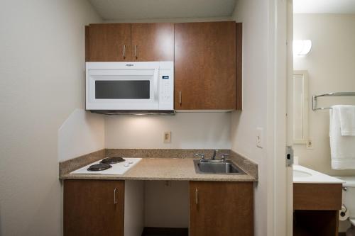 a small kitchen with a sink and a microwave at HomeTowne Studios by Red Roof Seattle - Kent/Des Moines in Des Moines