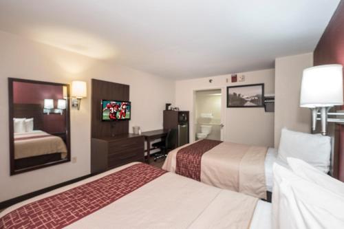 a hotel room with two beds and a flat screen tv at Red Roof Inn Lancaster in Lancaster