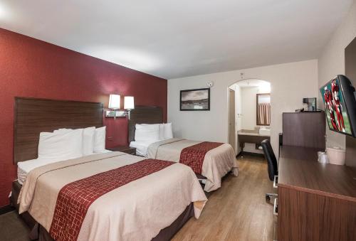 a hotel room with two beds and a flat screen tv at Red Roof Inn Lancaster in Lancaster