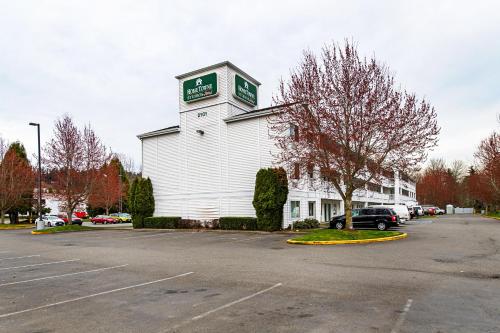 a white building with a clock tower in a parking lot at HomeTowne Studios by Red Roof Tacoma - Puyallup in Puyallup