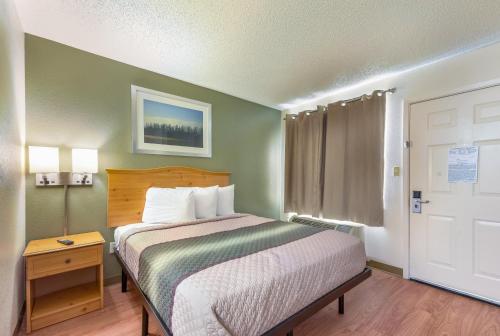 a small bedroom with a bed and a door at HomeTowne Studios by Red Roof Dallas - North Addison - Tollway in Addison