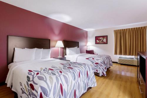 two beds in a hotel room with red walls at Red Roof Inn Carrollton in Carrollton