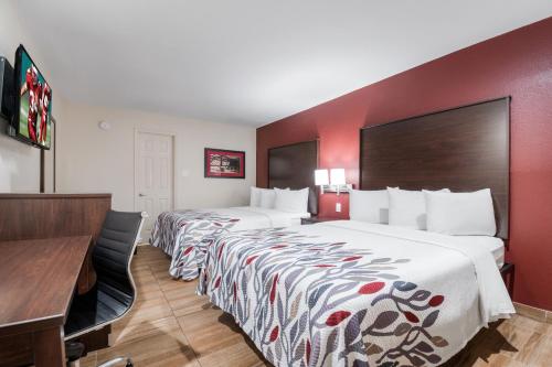 a hotel room with two beds and a desk at Red Roof Inn Houston – Spring North in Spring