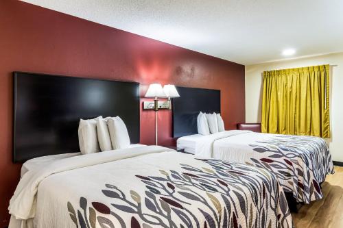 2 Betten in einem Hotelzimmer mit roten Wänden in der Unterkunft Red Roof Inn Atlanta - Kennesaw State University in Kennesaw