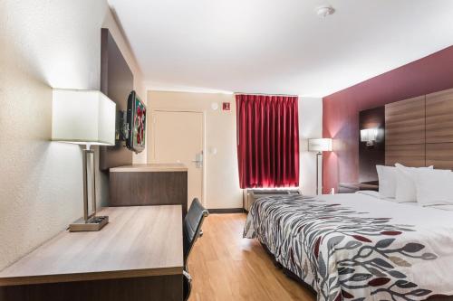 a hotel room with a bed and a red curtain at Red Roof Inn Texarkana in Texarkana