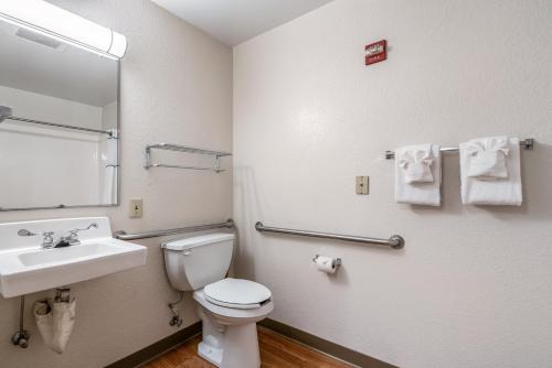 a bathroom with a toilet and a sink and a mirror at HomeTowne Studios by Red Roof Spokane - Valley in Spokane Valley