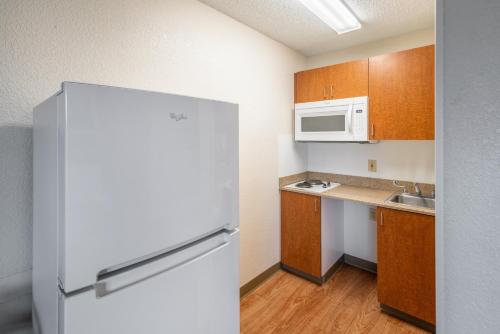 a small kitchen with a refrigerator and a microwave at HomeTowne Studios by Red Roof Spokane - Valley in Spokane Valley