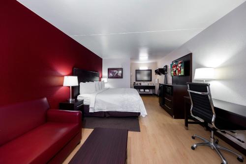 a hotel room with a bed and a red wall at Red Roof Inn PLUS+ Huntsville – Madison in Madison