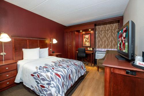 Habitación de hotel con cama y escritorio con TV. en RedRoof Inn, Meriden, CT, en Meriden