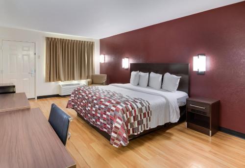 a large hotel room with a bed and a table at Red Roof Inn & Suites Commerce - Athens in Commerce