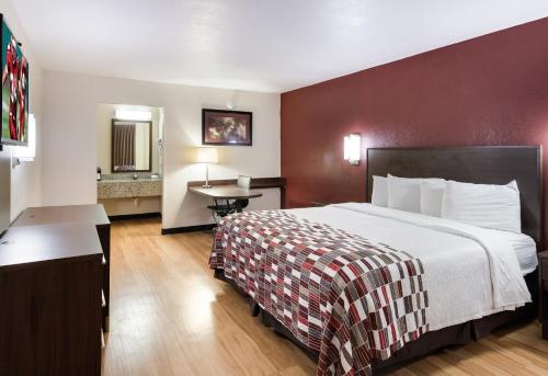 a hotel room with a large bed and a table at Red Roof Inn & Suites Commerce - Athens in Commerce