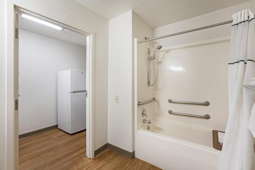 a bathroom with a tub and a shower stall with a refrigerator at HomeTowne Studios by Red Roof Detroit - Livonia in Livonia