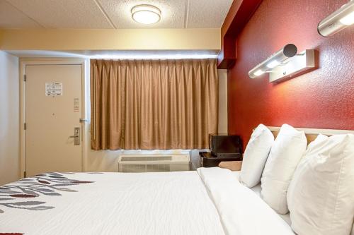 a hotel room with a large bed with white pillows at Red Roof Inn Johnson City in Johnson City