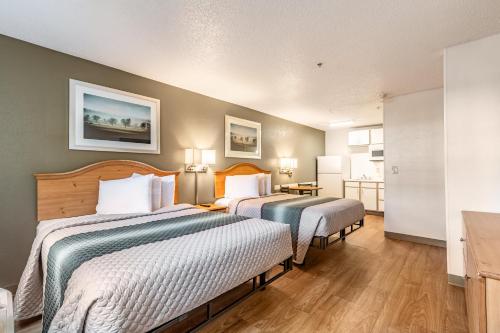 a hotel room with two beds and a kitchen at HomeTowne Studios by Red Roof Atlanta NE - Peachtree Corners in Norcross