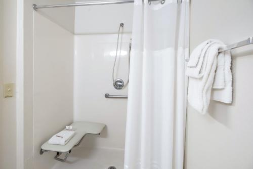 ein weißes Bad mit einem Duschvorhang und einem Waschbecken in der Unterkunft HomeTowne Studios by Red Roof Colorado Springs - Airport in Colorado Springs