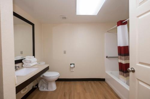 a bathroom with a toilet and a sink and a tub at Red Roof Inn PLUS+ & Suites Opelika in Opelika