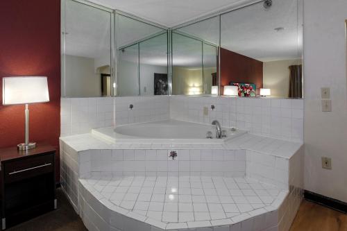 a large white bath tub with a large mirror at Red Roof Inn PLUS+ & Suites Opelika in Opelika