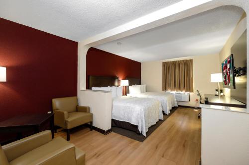 a hotel room with two beds and a chair at Red Roof Inn PLUS+ & Suites Opelika in Opelika