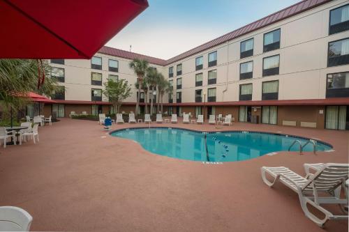 a pool in front of a hotel with chairs and a building at Red Roof Inn Myrtle Beach Hotel - Market Commons in Myrtle Beach