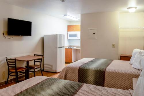 a hotel room with two beds and a table and a refrigerator at HomeTowne Studios by Red Roof Salem, OR in Salem