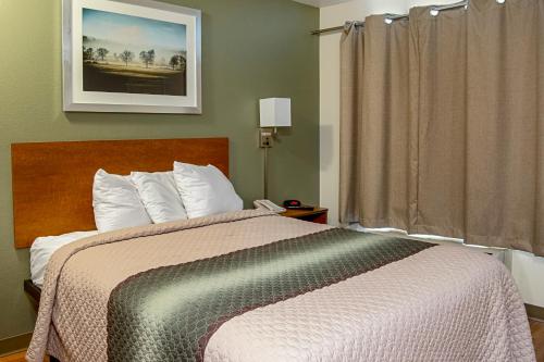 a bed in a hotel room with a window at HomeTowne Studios by Red Roof Salem, OR in Salem