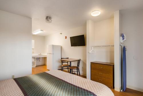 a bedroom with a bed and a desk and a kitchen at HomeTowne Studios by Red Roof Denver - Glendale/ Cherry Creek in Denver