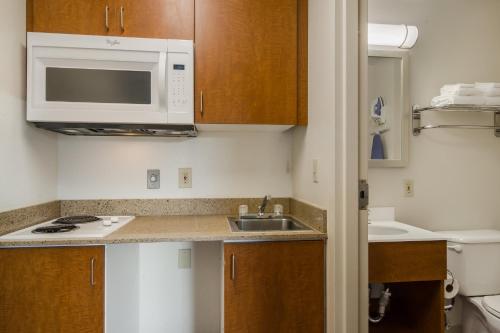 a small kitchen with a sink and a microwave at HomeTowne Studios by Red Roof Denver - Glendale/ Cherry Creek in Denver