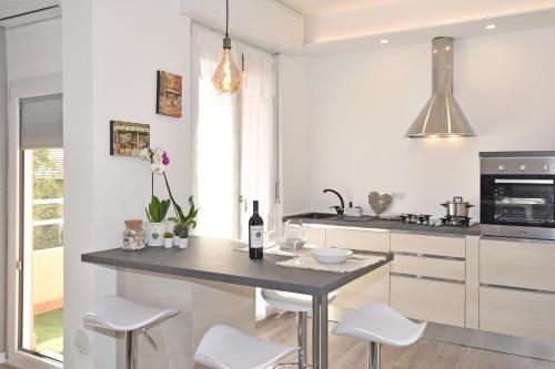 a kitchen with white cabinets and a table with white stools at LE PETIT BONHEUR in Como