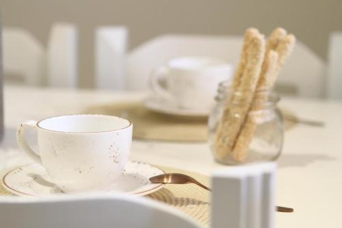 a coffee cup and saucer with bread in a glass jar at Navigator Villas - Houses in Acharavi